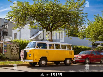 Camionnette camping-car Volkswagen Type 2 classique jaune et blanc garée sous un arbre dans une rue résidentielle d'East Vancouver, Colombie-Britannique. Banque D'Images