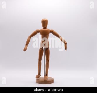 Un mannequin d'artiste en bois avec articulations debout dans une pose neutre sur un fond blanc. Banque D'Images