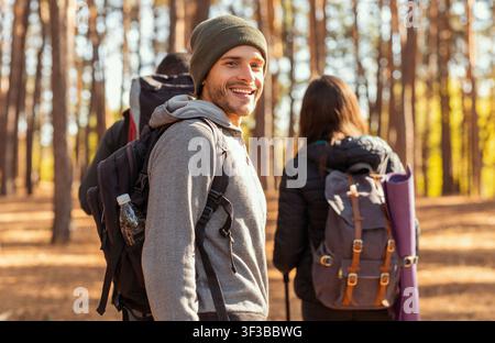 Souriant jeune homme randonneur avec des amis à la forêt Banque D'Images