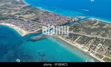 Prise de vue par drone capturant Nea Poteidaia en Grèce avec des plages de sable, des quartiers résidentiels animés, des oliveraies et une mer d'un bleu éclatant par une journée ensoleillée. Banque D'Images