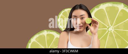 Jeune femme asiatique tenant une tranche de citron vert et souriant, concept de santé Banque D'Images