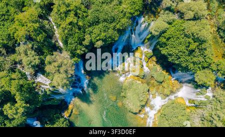 Vue aérienne par drone d'une rivière cristalline traversant un paysage verdoyant Banque D'Images