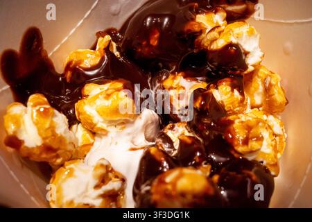 Popcorn arrosé de chocolat avec crème fouettée dans un récipient Banque D'Images