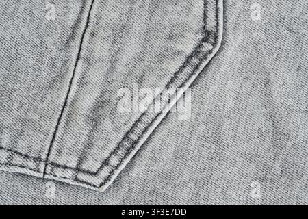 Texture macro détaillée d'un tissu denim gris délavé avec couture de poche en gros plan Banque D'Images