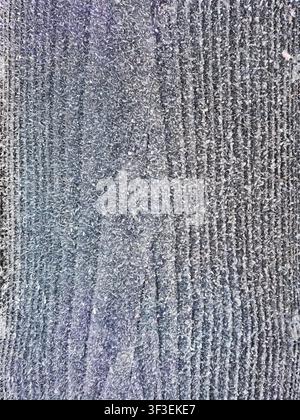 Cette image présente un gros plan détaillé de givre et de cristaux de glace sur une surface texturée Banque D'Images