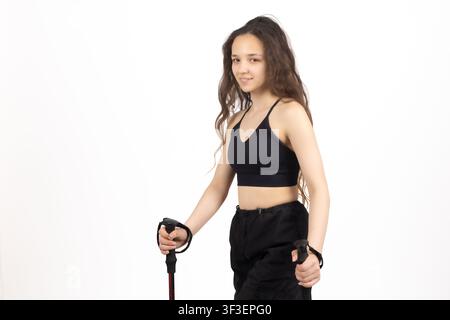 Jeune femme athlétique tenant des bâtons de trekking posant en studio isolée Banque D'Images