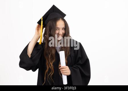 Jeune étudiante diplômée en casquette ajustant le pompon sur la casquette carrée Banque D'Images