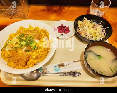 Un repas traditionnel japonais (teishoku) servi sur un plateau crème, comprenant un grand bol de katsudon – escalope de porc panée (tonkatsu) cuite Banque D'Images