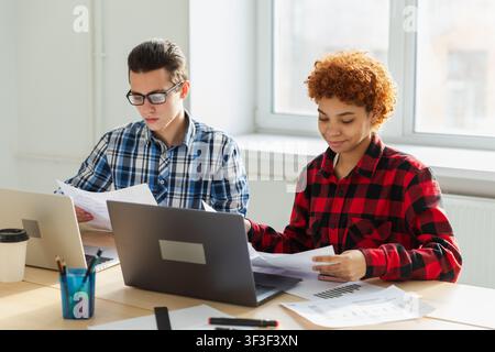 Brainstorming de travail d'équipe. Divers collègues travaillant ensemble discutent de statistiques financières. Groupe de jeunes gens modernes heureux assis dans un bureau créatif discutant des affaires. Jeune équipe professionnelle Banque D'Images
