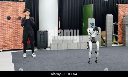 SHANGHAI, CHINE - 19 JUILLET 2026 - Un membre du personnel recueille des données de mouvement précises du robot Unitree en portant des équipements spéciaux tels que des vêtements de capture de mouvement dans la zone d'entraînement spécialisée en opération cérébrale contrôlée pour tout le corps du Premier Centre de démonstration chinois pour l'entraînement IA incarné, construit par le Centre d'innovation en robotique humanoïde construit conjointement par le National et Local et Huawei, Shanghai, Chine, le 19 juillet 2026. Banque D'Images