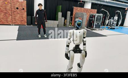 SHANGHAI, CHINE - 19 JUILLET 2026 - Un membre du personnel recueille des données de mouvement précises du robot Unitree en portant des équipements spéciaux tels que des vêtements de capture de mouvement dans la zone d'entraînement spécialisée en opération cérébrale contrôlée pour tout le corps du Premier Centre de démonstration chinois pour l'entraînement IA incarné, construit par le Centre d'innovation en robotique humanoïde construit conjointement par le National et Local et Huawei, Shanghai, Chine, le 19 juillet 2026. Banque D'Images