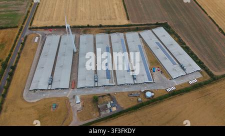 Vue aérienne d'une grande exploitation agricole avec de longues étables, une éolienne et des panneaux solaires sur les toits, située dans les champs ruraux de Mansfiel Banque D'Images