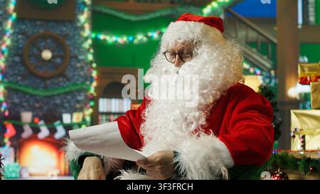 Le Père Noël secoue la tête, fait signe les pouces vers le bas, désaccord avec les lettres des enfants. Personne en costume de Noël faisant un geste de rejet négatif concernant les listes de souhaits des enfants, caméra A. Banque D'Images