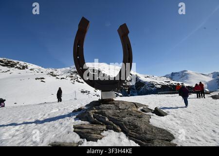 Grande sculpture publique en forme de fer à cheval dans un paysage montagneux enneigé avec des visiteurs Banque D'Images