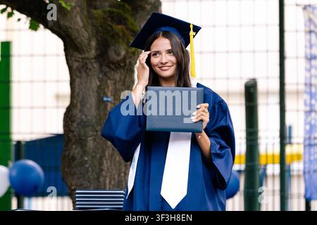 Jeune diplômée heureuse tenant fièrement son diplôme Banque D'Images