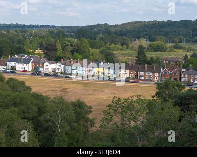 LONDON - 19 JUIN 2026 : Flanchford Road, Reigate Heath – Vue aérienne de maisons en rangée pastel colorées avec la campagne des Surrey Hills au loin. Banque D'Images