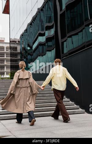 Jeune couple vêtu élégamment en tenue d'automne marche main dans la main le long des rues de la ville Banque D'Images