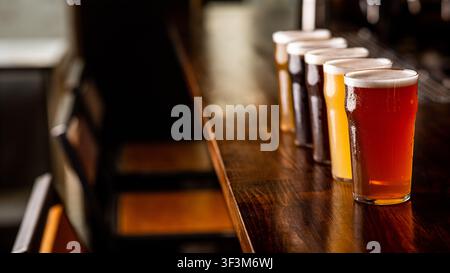 Faites la fête avec des amis au pub. Rangée de verres de bière de différentes sortes sur le comptoir du bar à l'intérieur Banque D'Images