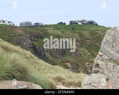 Le NC500 écossais : camping-cars, caravanes et fourgonnettes garés sur la pointe des falaises à Durness avec une vue spectaculaire sur la côte nord. Banque D'Images