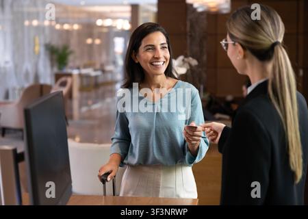 Client d'hôtel recevant une carte-clé au comptoir de réception Banque D'Images