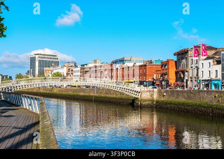 Vue large du pont Ha Penny franchissant la rivière Liffey au centre de Dublin, Irlande. Le pont piéton blanc relie des quais animés bordés d’hist… Banque D'Images