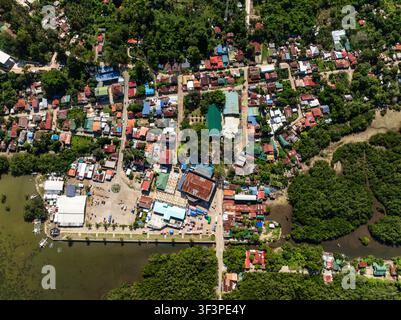 Vue aérienne d'une ville côtière aux toits colorés bordant une forêt de mangroves dense. San Francisco. Camotes, Philippines. Banque D'Images