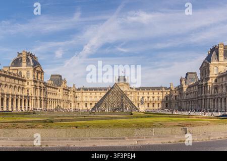 PARIS, FRANCE - 25 JUIN 2026 : Pyramide de verre emblématique et façade historique du palais du musée du Louvre Banque D'Images