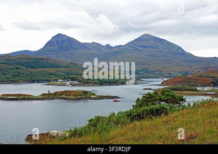Vue sur le Loch Glendhu vers le pont de Kylesku, et le hameau de Kylesku visible au bord de l'eau, avec les deux pics du Quinag s'élevant en arrière-plan. Banque D'Images