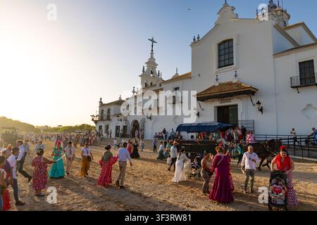Pèlerins de la Romería de El Rocío à cheval en tenue andalouse traditionnelle traje corto et robes flamenco rassemblés devant l’Ermita de El Rocío blanche Banque D'Images