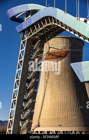 Close-up d'une tour de saut à ski moderne en Chine, montrant des escaliers en acier, un pont courbé et une base en béton sous un ciel bleu profond, mettant en valeur l'architecture sportive Banque D'Images