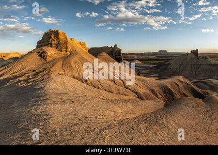 Paysage de badlands ensoleillé avec des formations de grès escarpées et des collines érodées sous un vaste ciel bleu, mettant en valeur le terrain désertique aride de l'Amérique Banque D'Images