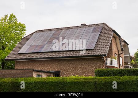 Panneaux solaires sur le toit d'une maison moderne installés sur un bâtiment résidentiel en brique dans une banlieue européenne pour la production d'énergie verte renouvelable et propre. Banque D'Images