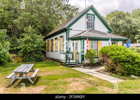 Le musée Old School House est une école à une salle datant des années 1830, abritant des artefacts d'excavations archéologiques. Le bâtiment en bois blanc, avec des volets jaunes et un drapeau canadien, se dresse sur les terrains du site du patrimoine des loyalistes noirs sur Old Birchtown Road près de Shelburne, en Nouvelle-Écosse, Canada. Municipalité du district de Shelburne, Nouvelle-Écosse, Canada Banque D'Images