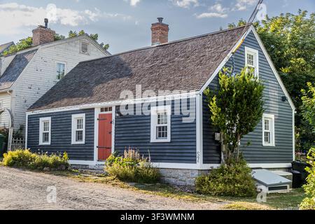 Une maison bleu foncé de style Cape Cod avec une porte rouge (numéro 57) dans la vieille ville de Lunenburg, en Nouvelle-Écosse, vue de l'autre côté de la rue, avec une double cheminée et une petite lucarne. Les maisons historiques à charpente en bois de ce style caractérisent les rues latérales du quartier classé au patrimoine mondial de l'UNESCO. Lunenburg, Nouvelle-Écosse, Canada Banque D'Images