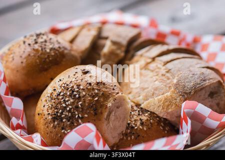 Pain Sourdough artisanal et petits pains aux graines servis dans un panier sur une table en bois Banque D'Images