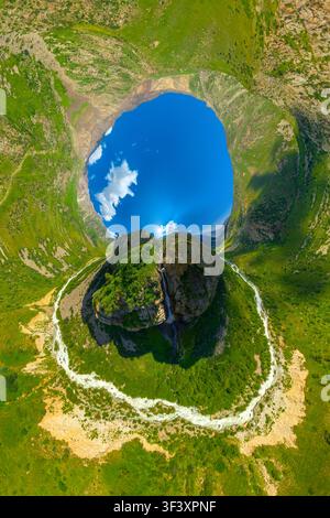 La perspective aérienne capture les montagnes Rocheuses ornées de verdure luxuriante et d'une rivière sinueuse en projection hyperbolique. Ciel bleu vif et cascade Wat Banque D'Images