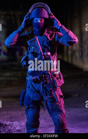 Soldat tactique dans un environnement urbain nocturne portant un casque et un équipement balistique avec un fusil d'assaut Banque D'Images