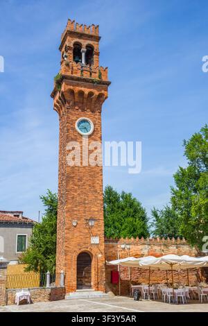 Tour d'horloge historique en brique se dresse à côté d'une terrasse de restaurant en plein air à Murano, Venise, Italie Banque D'Images