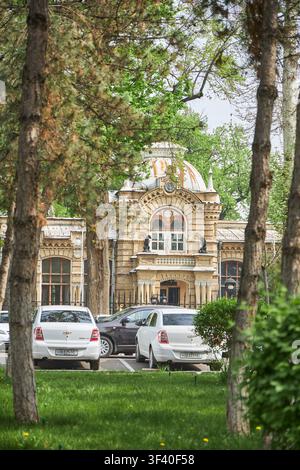 Grande résidence du prince Romanov avec architecture en brique visible à travers les arbres. Façade historique d’un bâtiment avec toit en dôme. Monument emblématique du patrimoine et de la culture. Tachkent, Ouzbékistan - 3 AVR 2026. Banque D'Images