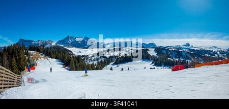 Vue panoramique hivernale d'une piste de ski avec deux skieurs non identifiables, neige préparée, paysage alpin et grand espace de copie dans la station de ski de Corvara, Alta Badia Banque D'Images