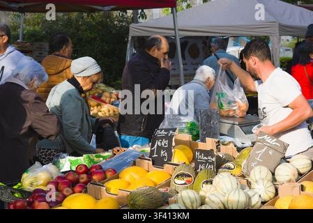 Un vendeur pèse des melons pour les clients sur un marché de fruits en plein air animé à Arles, en France. Banque D'Images