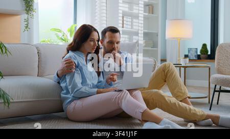 Pensif inquiet perplex regardant dans un ordinateur portable en attendant les résultats en ligne, homme pensif avec une femme ressentant l'inquiétude, regard pensif sur l'écran d'ordinateur, famille Banque D'Images
