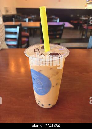 Thé au lait glacé Boba avec perles de tapioca et motif de couvercle de dessin animé sur une table en bois Banque D'Images