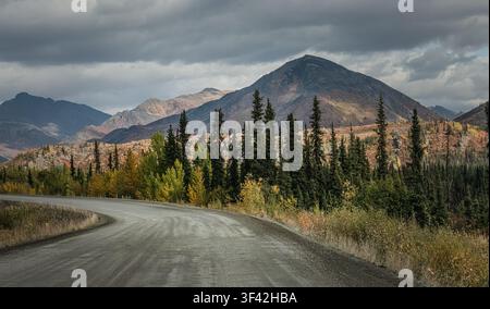 Une route de gravier serpente à travers la forêt boréale et la toundra ouverte le long de la Dempster Highway au Yukon, Canada. Les couleurs automnales se répandent à travers les bouleaux et les trembles Banque D'Images