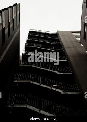 Escalier d'évacuation incendie extérieur en zigzag montant un bâtiment sombre sous un ciel couvert à Nishi-Shinjuku, Tokyo, Japon Banque D'Images
