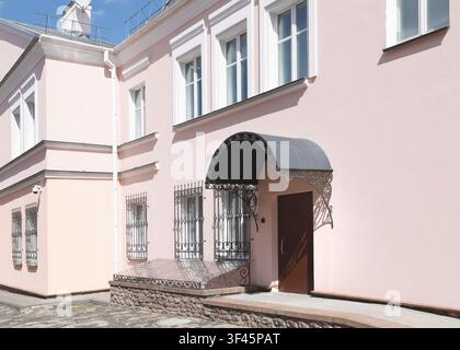 Architecture européenne classique, extérieur d’un manoir de vieille ville. Façade de maison classique traditionnelle avec murs rose pastel, cadres de fenêtres blancs et fer forgé Banque D'Images