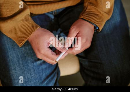 Homme adulte tenant une cigarette lors d'une séance de groupe de soutien Banque D'Images
