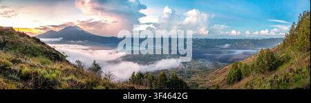 Paysage panoramique époustouflant au lever du soleil depuis le mont Batur à Kintamani, Bali, mettant en scène le lac Batur, les champs de lave noirs, la vallée de la caldeira, les collines de Trunyan et Banque D'Images