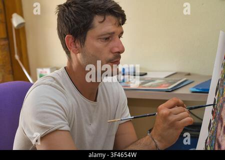 Artiste masculin concentré peignant dans son atelier Banque D'Images