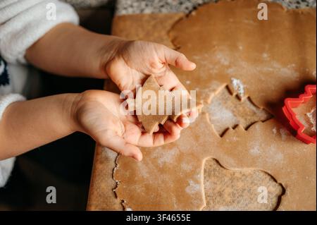 Enfant tenant une pâte à biscuits en forme de sapin de Noël fraîchement coupée Banque D'Images